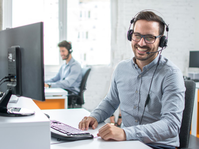 Online live chat - freundlicher, männlicher Servicemitarbeiter mit headset auf hellgrauem Hintergrund